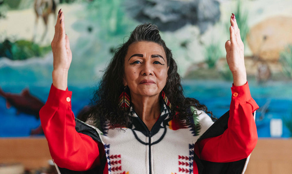 Indigenous elder woman with hands held up in gratitude