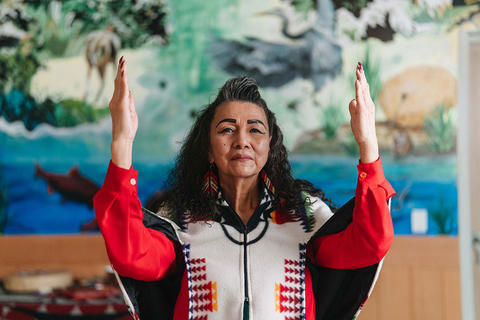 Indigenous elder woman with hands held up in gratitude